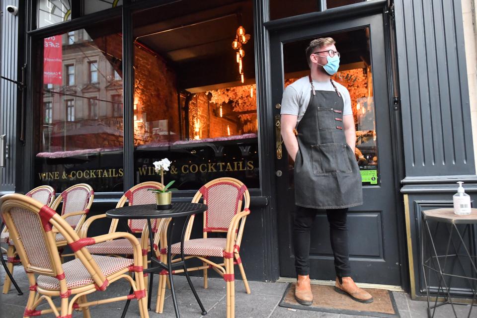 A bartender wearing a face mask stands outside a bar in Cardiff (PA) (PA Archive)