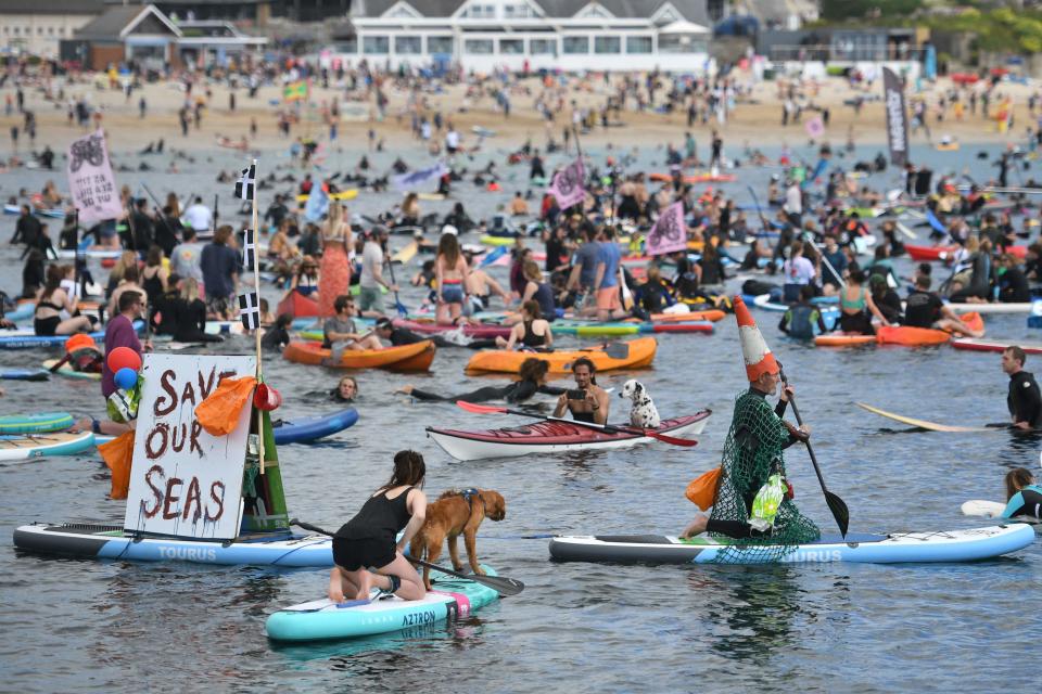 Surfers, paddleboarders and kayakers take part in an environmental protest in the water off Gyllyngvase beach in Falmouth, Cornwall during the G7 summit.