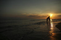 Tourists visit the beach of Antalya, southern Turkey, as the sun sets , on Sunday, June 20, 2021. Hotels in Turkey's Antalya region, a destination beloved by holidaymakers, are preparing to finally resume operations as they expect the return of international tourists after months of setbacks caused by the pandemic that halted travel. (AP Photo/Emrah Gurel)