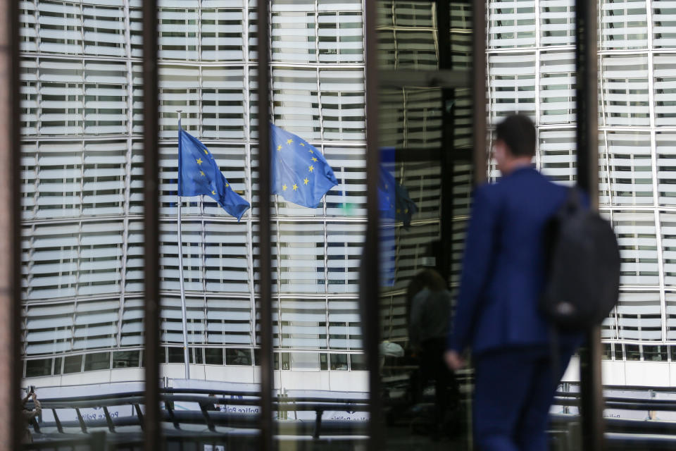 Reflection of European flags while a man enters a building. Flags of Europe waving as seen on a pole. The European Flag is the symbol of Council of Europe COE and the European Union EU as seen in the Belgian capital in front of modern architecture buildings with glass and steel construction the Le Berlaymont building, European Commission headquarters next to Forum Europa at the European Quarter in Brussels, where the headquarters of the pan-European institutions and organizations are located. Brussels, Belgium on October 2020 (Photo by Nicolas Economou/NurPhoto via Getty Images)