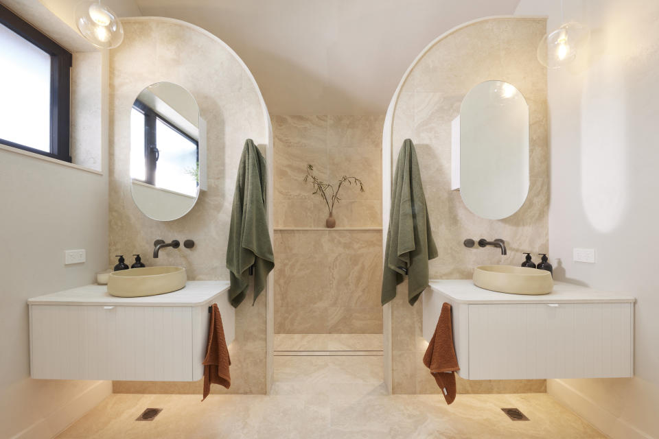 A shot of the bathroom with two arches on either side, and a vanity in front of each arch. 