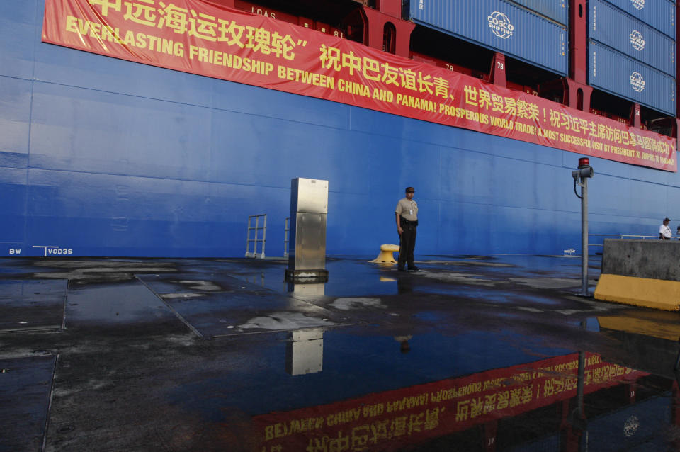 In this Dec. 3, 2018, photo, a Panama Canal guard stands at attention in front of a Chinese container ship docked at the Panama Canal's Cocoli Locks in Panama City, during an official visit by China's President Xi Jinping and first lady Peng Liyuan. China’s expansion in Latin America of its Belt and Road initiative to build ports and other trade-related facilities is stirring anxiety in Washington. As American officials express alarm at Beijing’s ambitions in a U.S.-dominated region, China has launched a charm offensive, wooing Panamanian politicians, professionals, and journalists. (AP Photo/Arnulfo Franco)