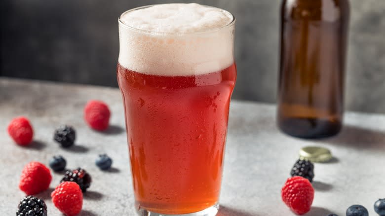 glass of beer surrounded by berries