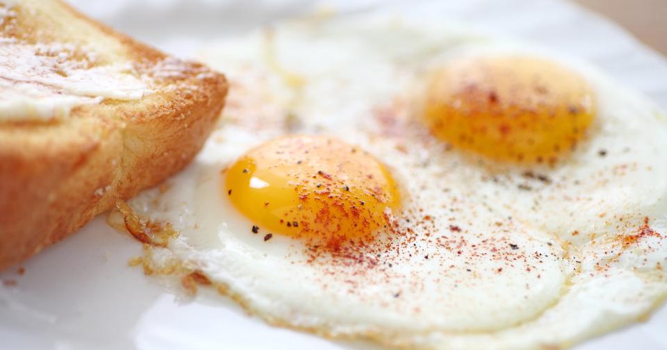 two fried eggs sunny side up, sprinkled with smoked paprika and black pepper, toast alongside