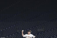 Tomoyuki Sugano of the Yomiuri Giants pitches with a backdrop of empty stands during play in a preseason baseball game between the Yomiuri Giants and the Yakult Swallows at Tokyo Dome in Tokyo Saturday, Feb. 29, 2020. Japan's professional baseball league said Thursday it will play its 72 remaining preseason games in empty stadiums because of the threat of the spreading coronavirus. (AP Photo/Eugene Hoshiko)