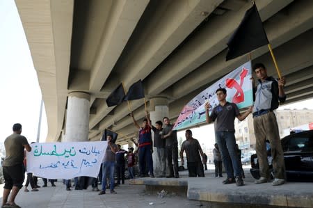 Shop owners and workers hold flags during a strike called by local activists against U.S. President Donald Trump's "Deal of the Century" at Al-Baqaa Palestinian refugee camp, near Amman