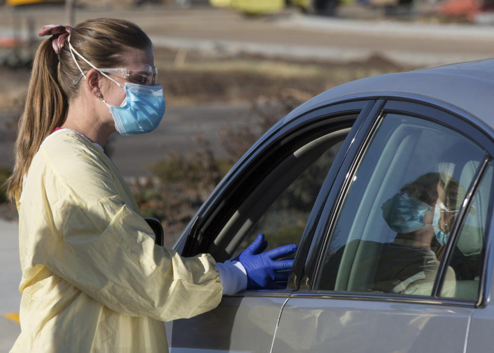 Physician assistant Nicole Thomas conducts a COVID-19 examination in the parking lot at Primary Health Medical Group's clinic in Boise, Idaho, Tuesday, Nov. 24, 2020. The urgent-care clinic revamped into a facility for coronavirus patients as infections and deaths surge in Idaho and nationwide. Some 1,000 people have died due to COVID-19, and infections this week surpassed 100,000. (AP Photo/Otto Kitsinger)