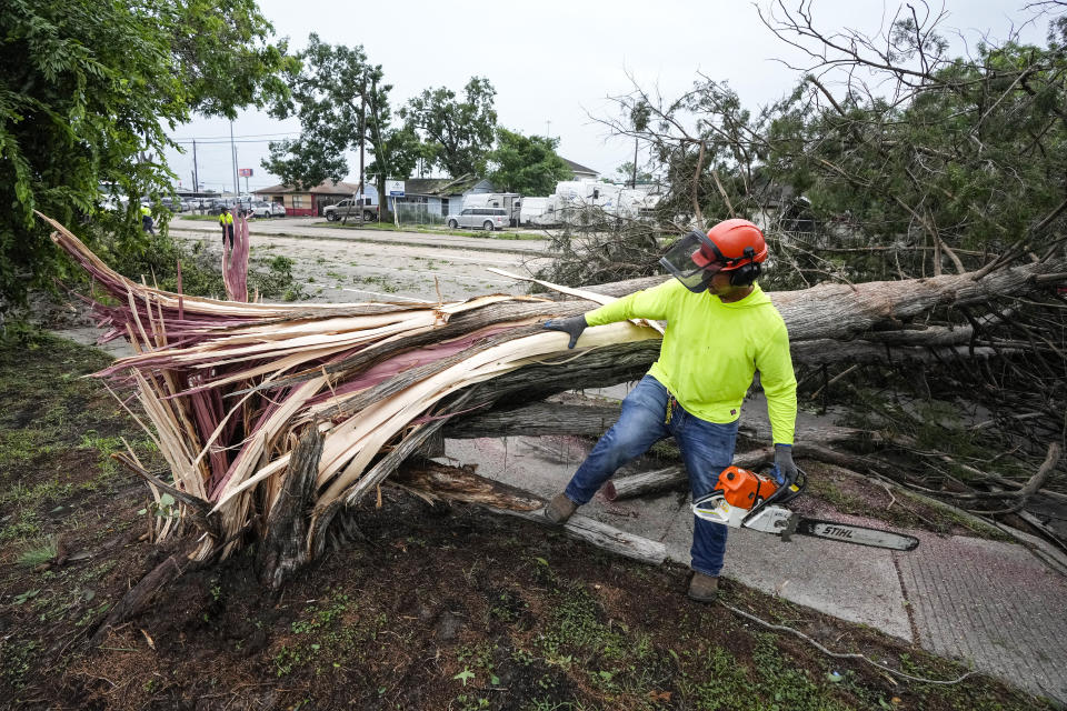 Dionysius Torreros, of the City of Houston, works on clearing a tree that toppled across Bingle Road in the aftermath of a severe storm on Friday, May 17, 2024, in Houston. The widespread destruction brought much of Houston to a standstill as crews raced to restore power and remove uprooted trees and debris. (Brett Coomer/Houston Chronicle via AP)