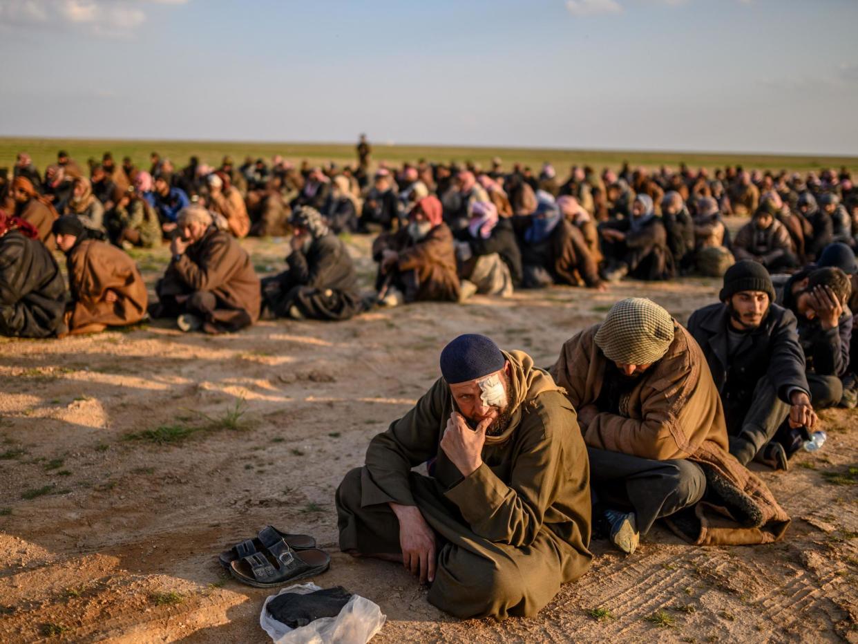 Suspected Isis fighters wait to be searched by the Kurdish-led SDF: AFP