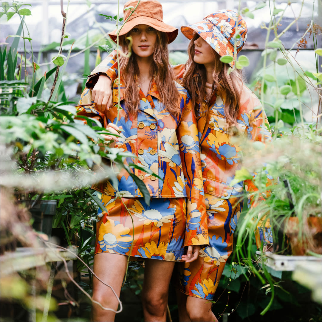  women in orange floral rain boots, jacket, hat, and skirt 