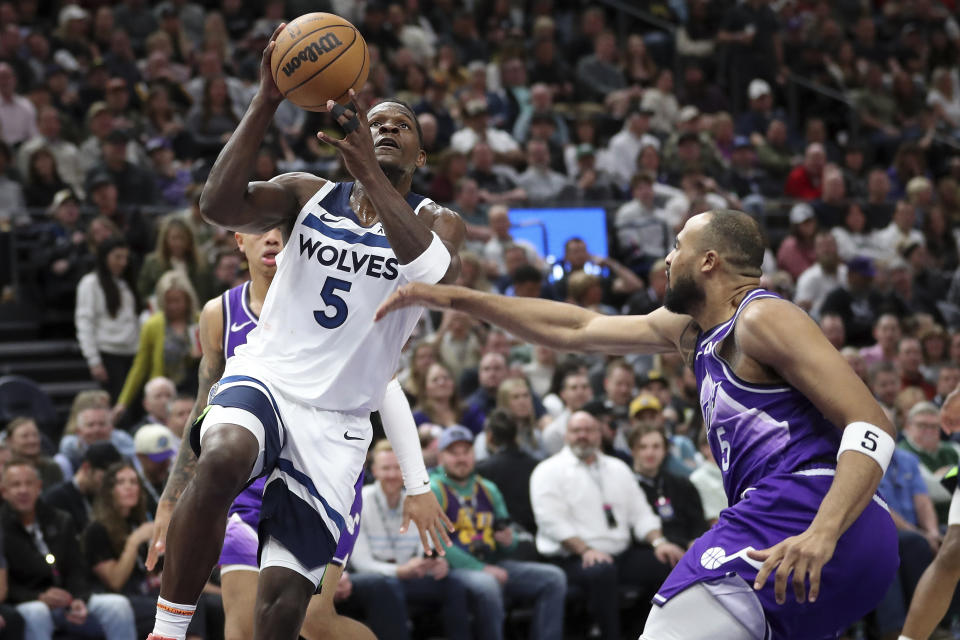 Minnesota Timberwolves guard Anthony Edwards, left, drives to the basket around Utah Jazz guard Talen Horton-Tucker during the second half of an NBA basketball game Monday, March 18, 2024, in Salt Lake City. (AP Photo/Adam Fondren)