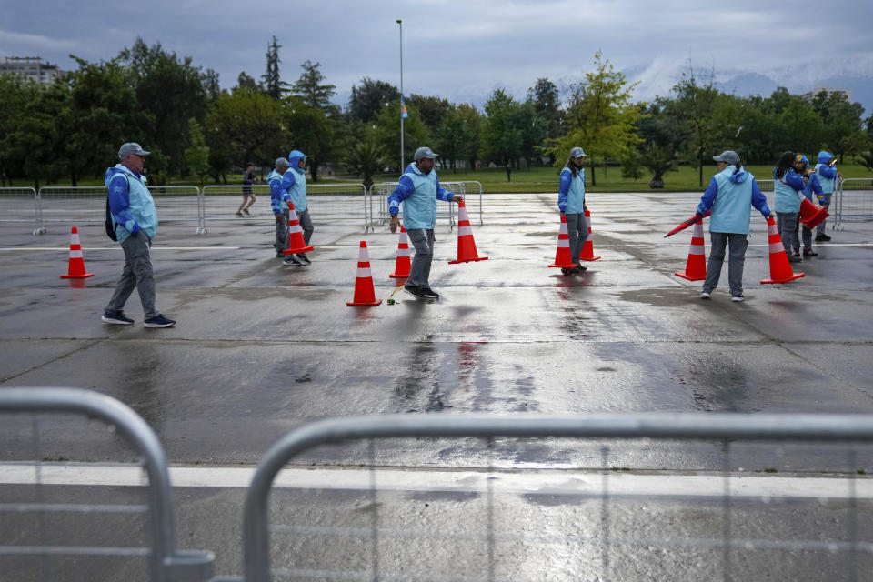 El personal reajusta los conos de la ruta de la marcha de 20 kilómetros de los Juegos Panamericanos en Santiago, Chile, el domingo 29 de octubre de 2023. (AP Foto/Moisés Castillo)