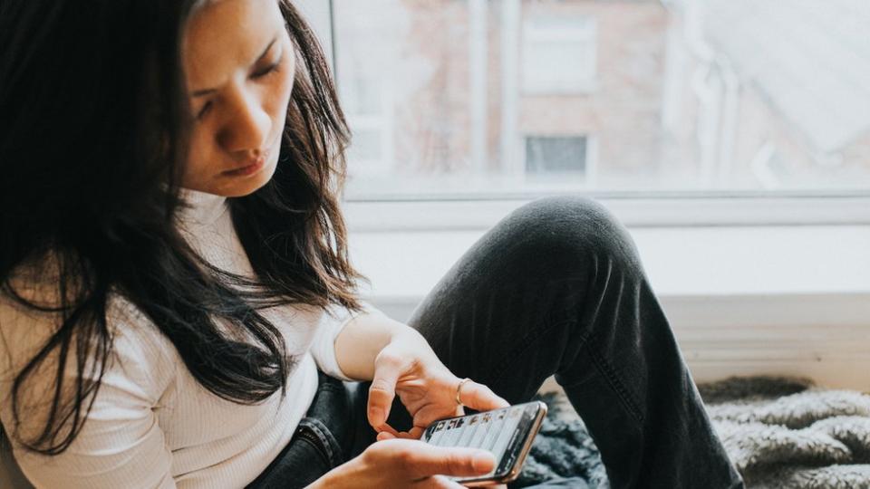 Una mujer frustrada mira su celular