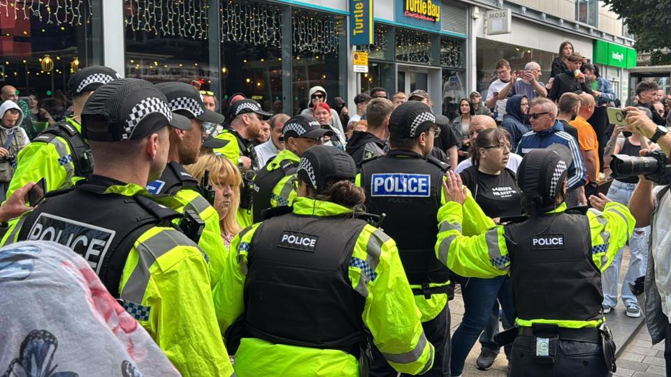 A number of police officers clash with protesters near to shops in Preston