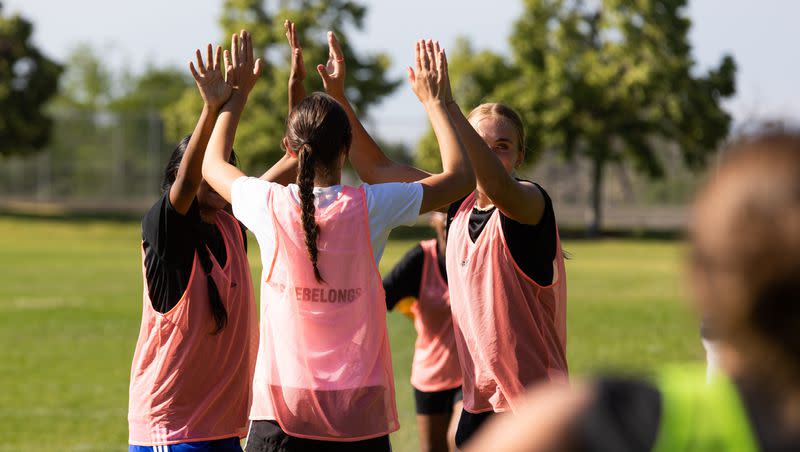 Anu Arumugarasa, of Sri Lanka, left, Sutton Hull, of Park City, and Eliza Collings,ot Alpine, high-five after scoring in a scrimmage at their #SheBelongs soccer practice at Lone Peak Park in Sandy on Thursday, July 6, 2023. #SheBelongs is a four-month program bringing together refugee and nonrefugee girls through soccer.