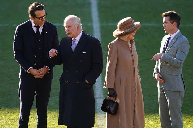 <p>Jacob King/PA Images via Getty Images</p> King Charles and Queen Camilla speak with Ryan Reynolds (far left) and Rob McElhenney (far right) at Wrexham Association Football Club's Racecourse Ground in December 2022.