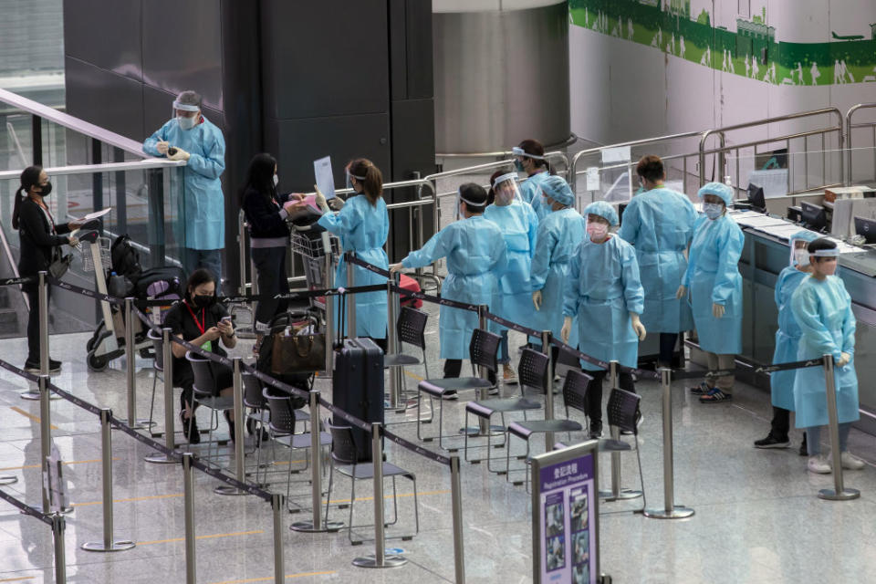 Healthcare workers wearing personal protective equipment (PPE) assist travelers heading to quarantine in the arrival hall at Hong Kong International Airport in Hong Kong, China, on Friday, April 1, 2022.<span class="copyright">Paul Yeung—Bloomberg/Getty Images</span>