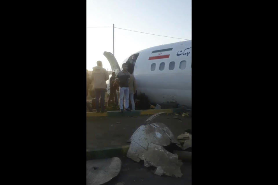 In this image from video shot by Iran's Civil Aviation Network News, passengers walk off a crashed plane in Mahshahr, Iran, Monday, Jan. 27, 2020. The Iranian passenger airliner carrying some 150 passengers skidded off the runway and into a street next to the airport in the southern city of Mahshahr on Monday, after apparently losing its landing gear in a hard landing. (Iran's Civil Aviation Network News via AP)