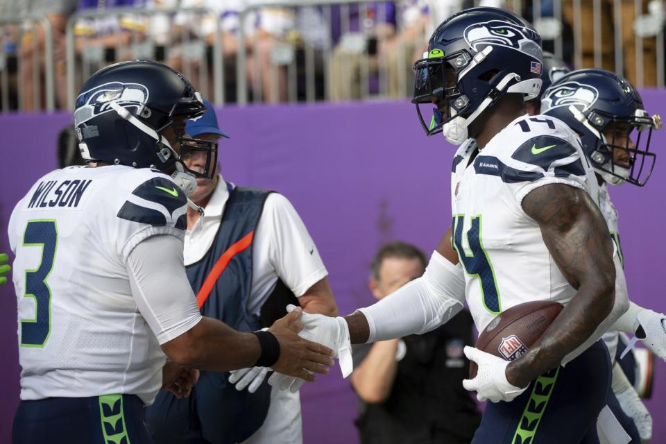 Seattle Seahawks quarterback Russell Wilson high fives wide receiver DK Metcalf.