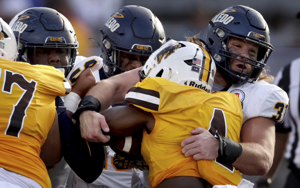Toledo linebacker Daniel Bolden, right, stops Wyoming running back Harrison Waylee (4) at the line on a second-quarter run during the Arizona Bowl NCAA college football game Saturday, Dec. 30, 2023, in Tucson, Ariz. (Kelly Presnell/Arizona Daily Star via AP)