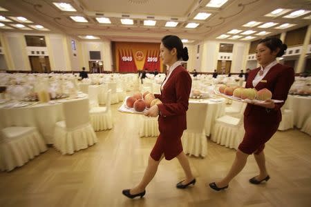 Attendants carry trays of peaches as they prepare for a reception marking the 61th anniversary of China at the Great Hall of the People in Beijing in this September 30, 2010 file photo. REUTERS/Jason Lee/Files