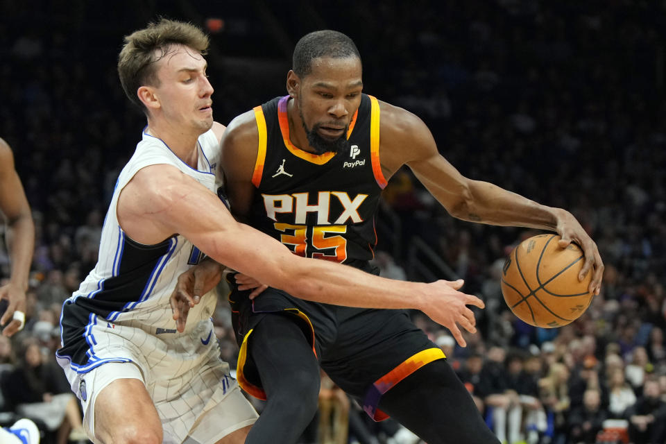 Phoenix Suns forward Kevin Durant shields the ball from Orlando Magic forward Franz Wagner during the first half of an NBA basketball game, Sunday, Dec. 31, 2023, in Phoenix. (AP Photo/Rick Scuteri)