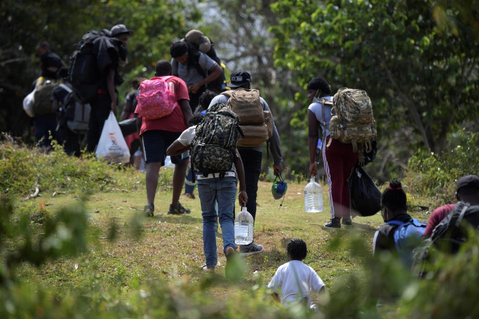 Migrants from Haiti, Cuba and several African nations who arrived to Capurgana from Necocli, both at the Caribbean Gulf of Uraba, northwestern Colombia, walk to try to cross illegally to Panama through the jungle, in Colombia, on 4 February, 2021.AFP via Getty Images
