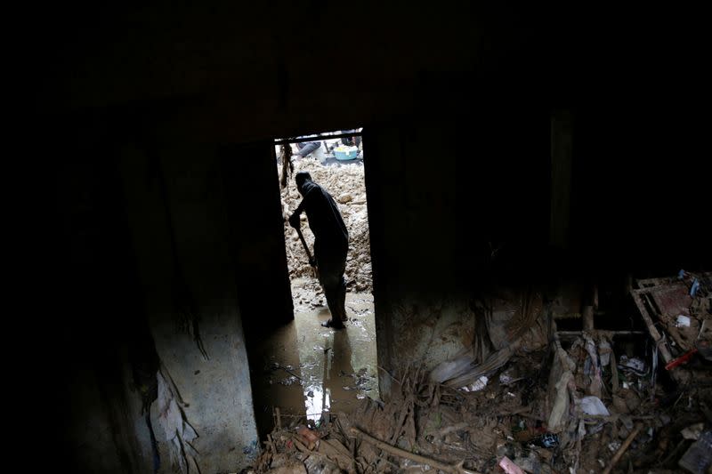 A man takes mud out of a store affected by the passage of Tropical Storm Laura, in Port-au-Prince