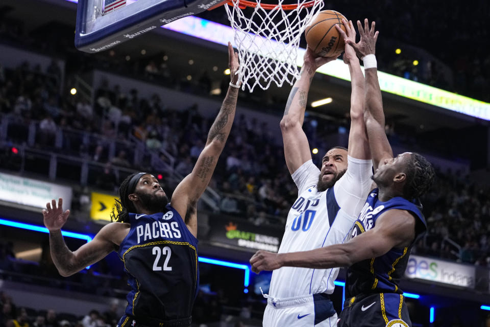 Dallas Mavericks center JaVale McGee (00) shoots between Indiana Pacers forward Isaiah Jackson (22) and forward Aaron Nesmith (23) during the first half of an NBA basketball game in Indianapolis, Monday, March 27, 2023. (AP Photo/Michael Conroy)