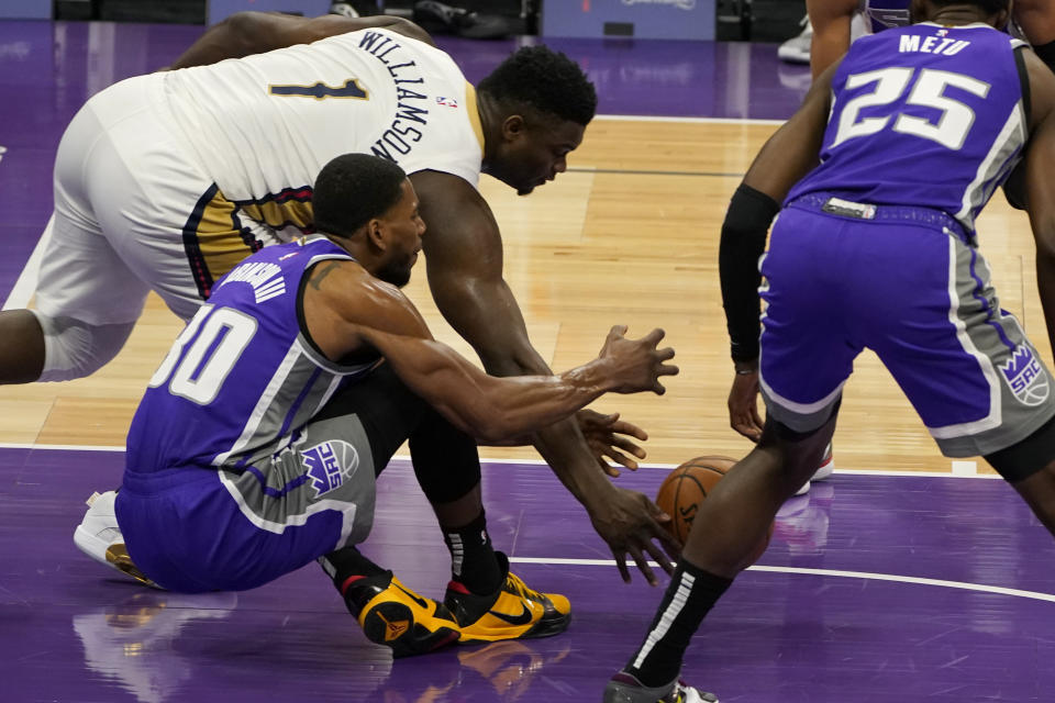 New Orleans Pelicans forward Zion Williamson, left, scoops up the loose ball against Sacramento Kings forward Glenn Robinson III, second from left, during the first quarter of an NBA basketball game in Sacramento, Calif., Sunday, Jan. 17, 2021. (AP Photo/Rich Pedroncelli)