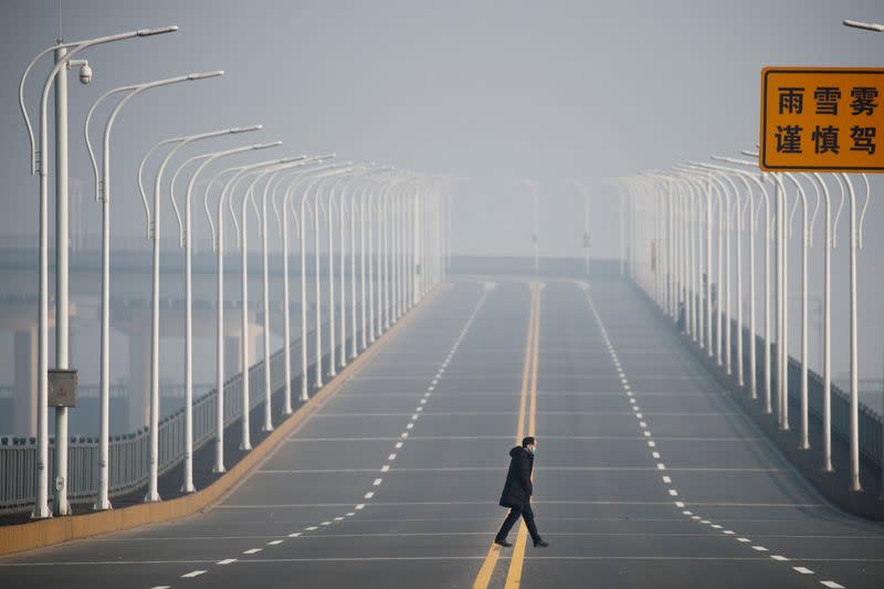 FILE PHOTO: A man who arrived from Hubei province crosses the Jiujiang Yangtze River Bridge near a checkpoint in Jiujiang