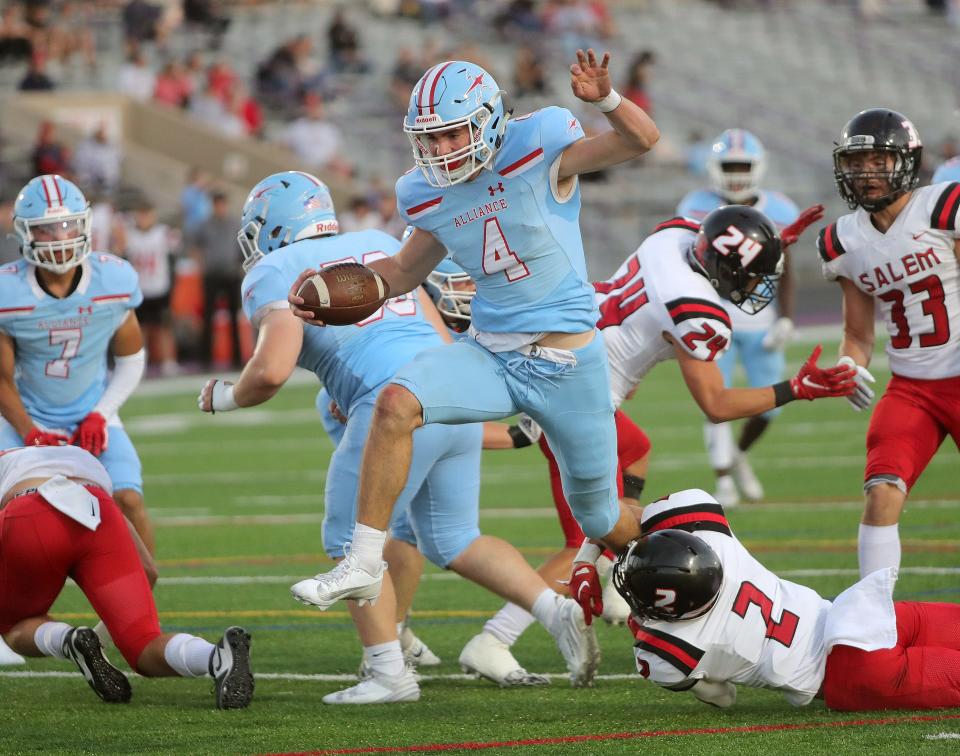 Alliance quarterback Brendan Zurbrugg leaps a Salem defender before crossing the goal line for a touchdown at Kehres Stadium, Friday, Sept. 22, 2023.