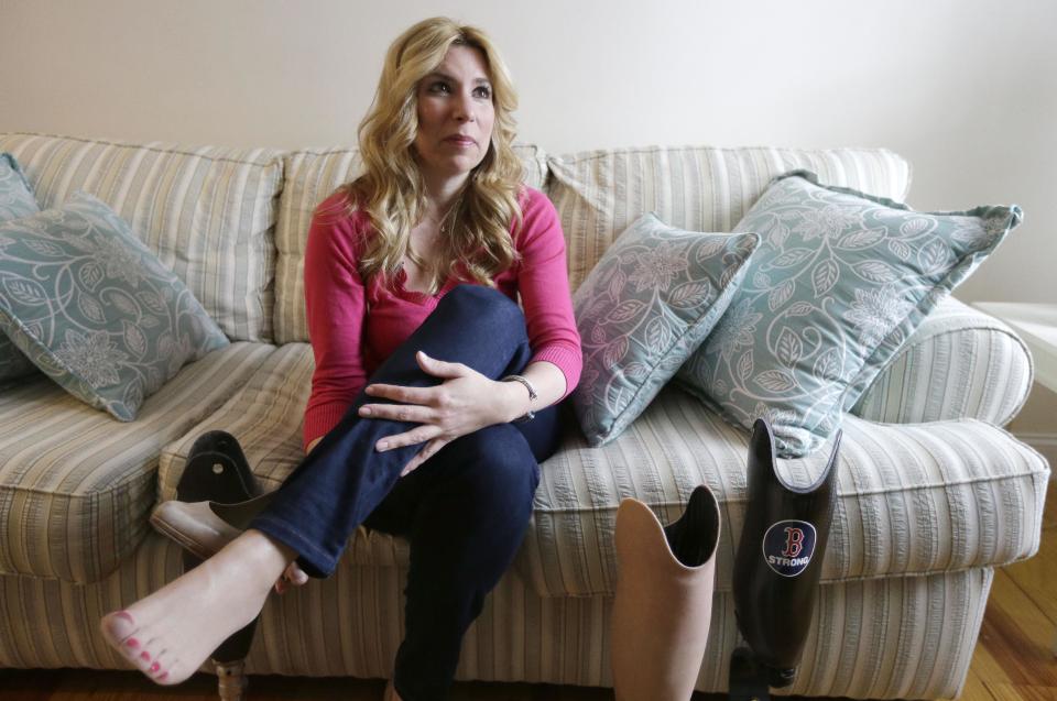 In this March 20, 2014 photo, Boston Marathon bombing survivor Heather Abbott, of Newport, R.I., speaks with a reporter at her home in Newport, R.I. Within four months of getting a prosthetic leg, Abbott went paddle boarding. Soon after, she got a special leg so she could walk in 4-inch heels, her preferred footwear. She also has a special running blade, as well as an “everyday” leg. (AP Photo/Steven Senne)