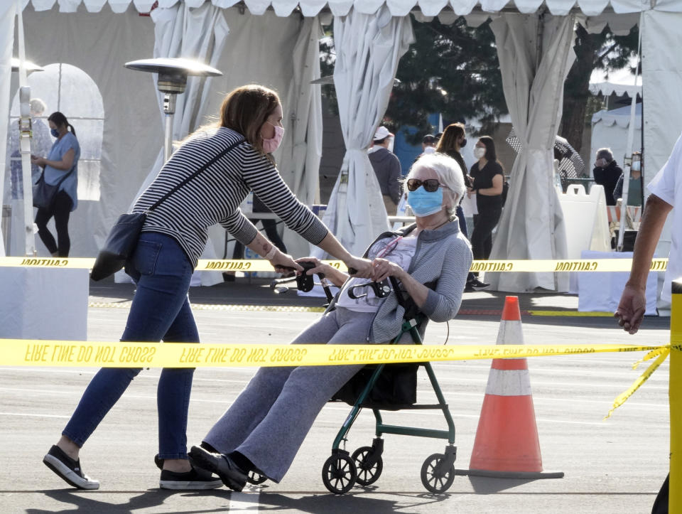 People walk after receiving their vaccines at the Disneyland Resort, serving as a Super POD (Point of Dispensing) COVID-19 mass vaccination site in Anaheim, Calif., Wednesday, Jan. 13, 2021. The parking lot is located off Katella Avenue and sits southeast of Disneyland. California is immediately allowing residents 65 and older to get scarce coronavirus vaccines, Gov. Gavin Newsom announced Wednesday. (AP Photo/Damian Dovarganes)