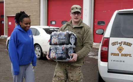 Michigan National Guard Staff Sergeant William Phillips (R) assists a Flint resident with bottled water at a fire station in Flint, Michigan January 13, 2016. REUTERS/Rebecca Cook