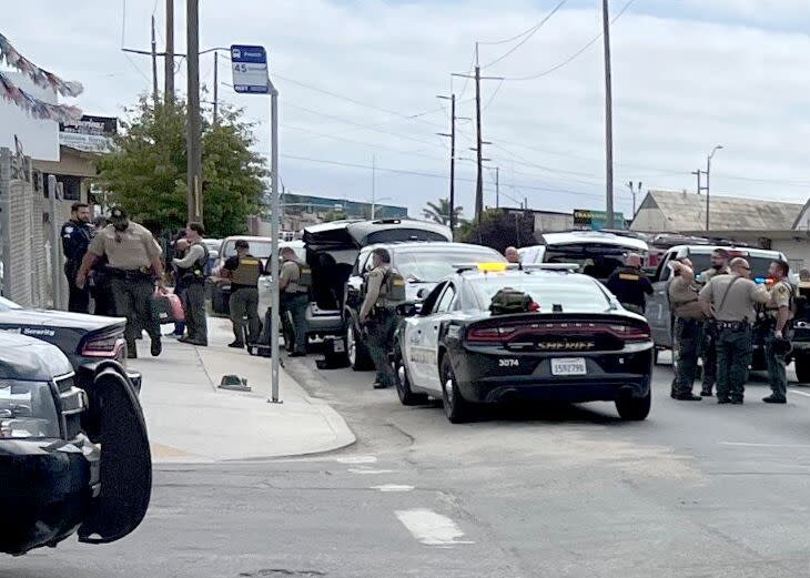 The Monterey County Sheriff's Department deputies and vehicles stand scattered on a corner of two streets.