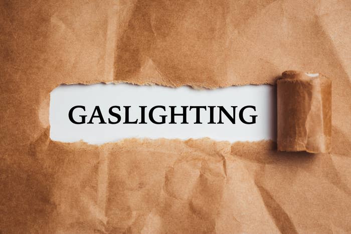 Torn brown paper revealing the word "GASLIGHTING" underneath