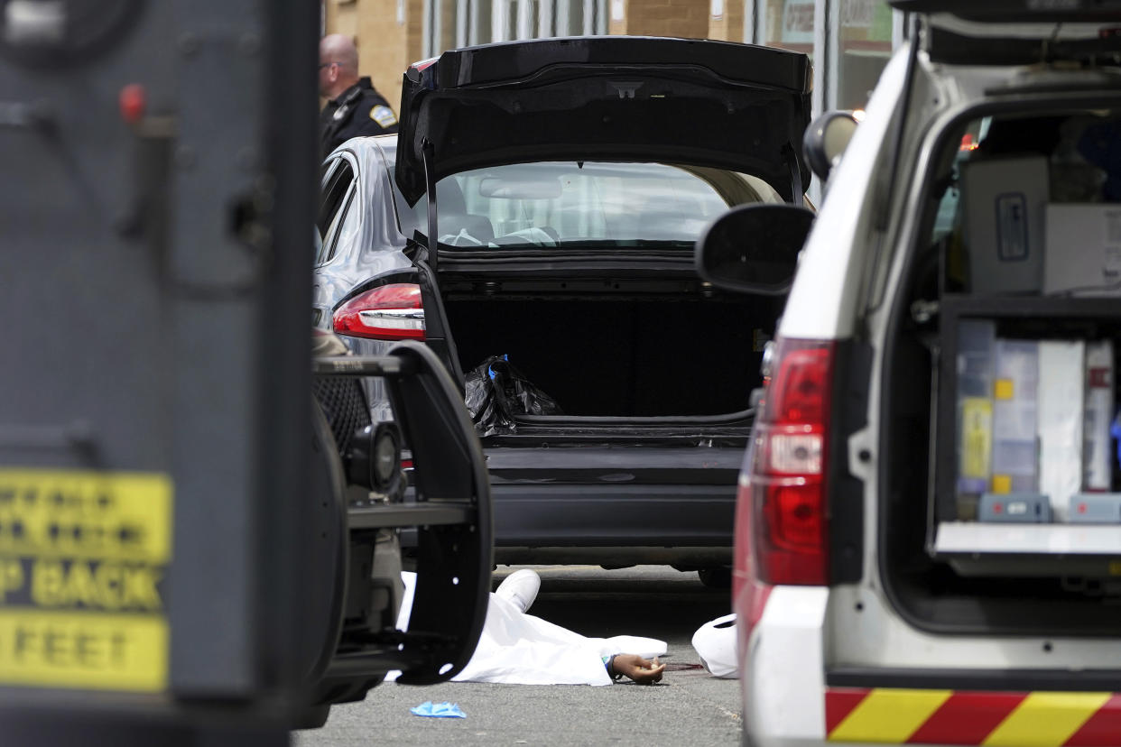 FILE - A body lies covered in the parking lot of Tops supermarket where several people were killed in a shooting, May 14, 2022 in Buffalo, N.Y. The city of Buffalo will pause Sunday, May 14, 2023 to mark the passing of one year since a gunman killed 10 people and injured three others in a racist attack that targeted Black people at a city supermarket.(Mark Mulville/The Buffalo News via AP, File)