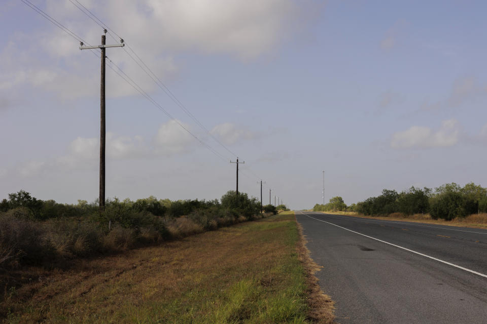 A portion of the Farm to Market 1017 roadway is shown, where water stations for immigrants containing sealed jugs of fresh water sit along fence lines in rural Jim Hogg County, Texas, Tuesday, July 25, 2023. The South Texas Human Rights Center maintains over 100 blue barrels consistently stocked with water across rural South Texas to serve as a life-saving measure for immigrants who have crossed into the United States to travel north in the sweltering heat. (AP Photo/Michael Gonzalez)