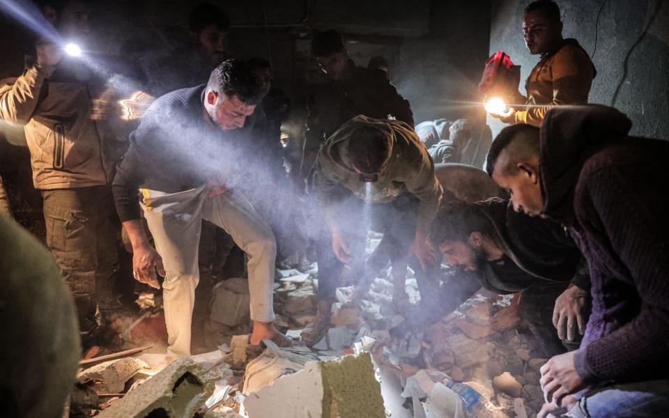 People struggle to recover bodies and injured people from under the rubble of a building struck by an Israeli raid on Rafah