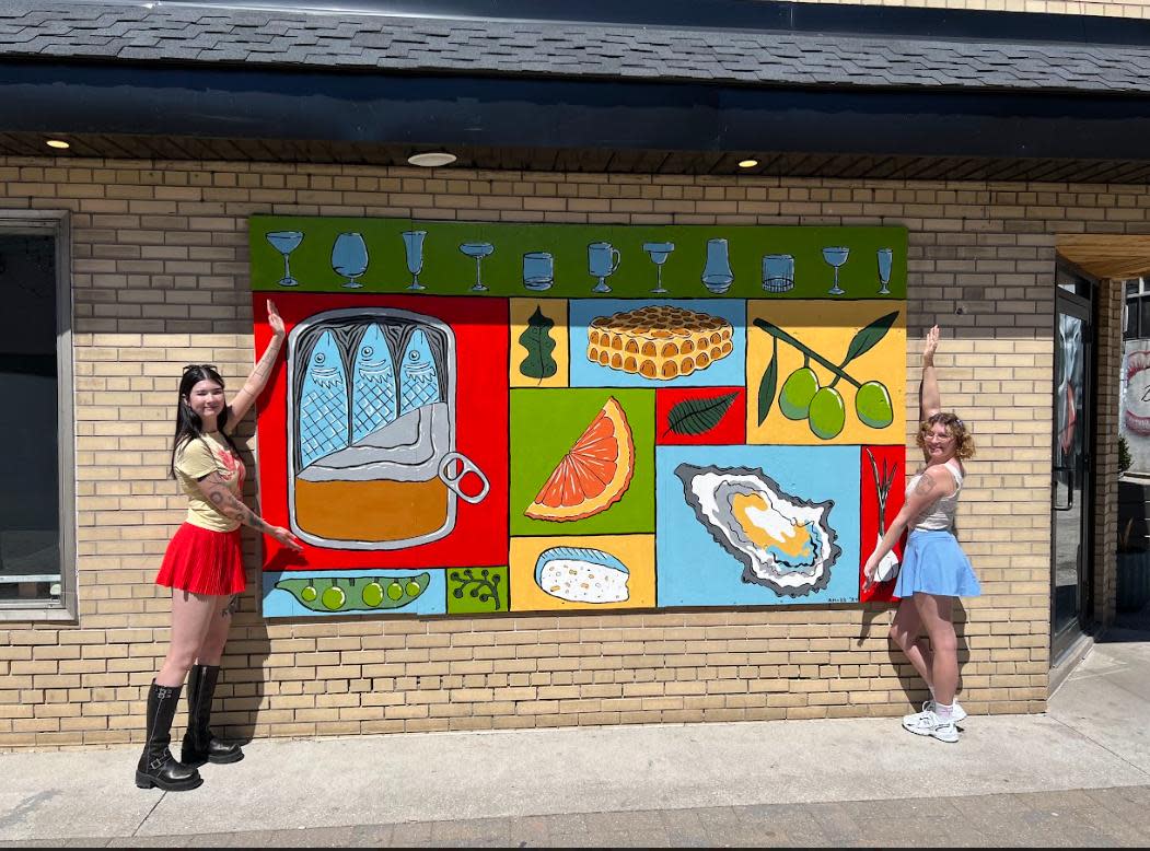 Best friends Alexandria Masse and Kaley Beecroft, 23, display their mural that covers the broken window at Maiden Lane Wine and Spirits in downtown Windsor, Ont.  (Josiah Sinanan / CBC News - image credit)