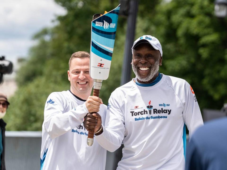 Olympic champion and former sprinter Bruny Surin, right, pictured with the Canada Games torch in Terrebonne, Que., in June.  (Submitted by Mathieu Barrette/Canada Games - image credit)