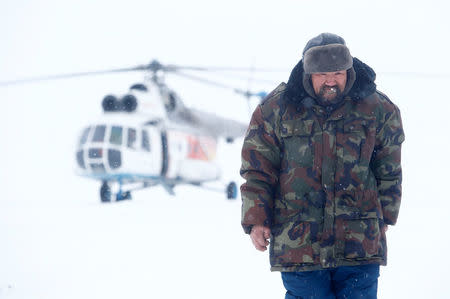 A herder of the agricultural cooperative organisation "Erv" walks in front of a helicopter at a reindeer camping ground, about 250 km north of Naryan-Mar, in Nenets Autonomous District, Russia, March 8, 2018. The helicopter was carrying local electoral commission members during the early voting in remote areas ahead of the presidential election. REUTERS/Sergei Karpukhin