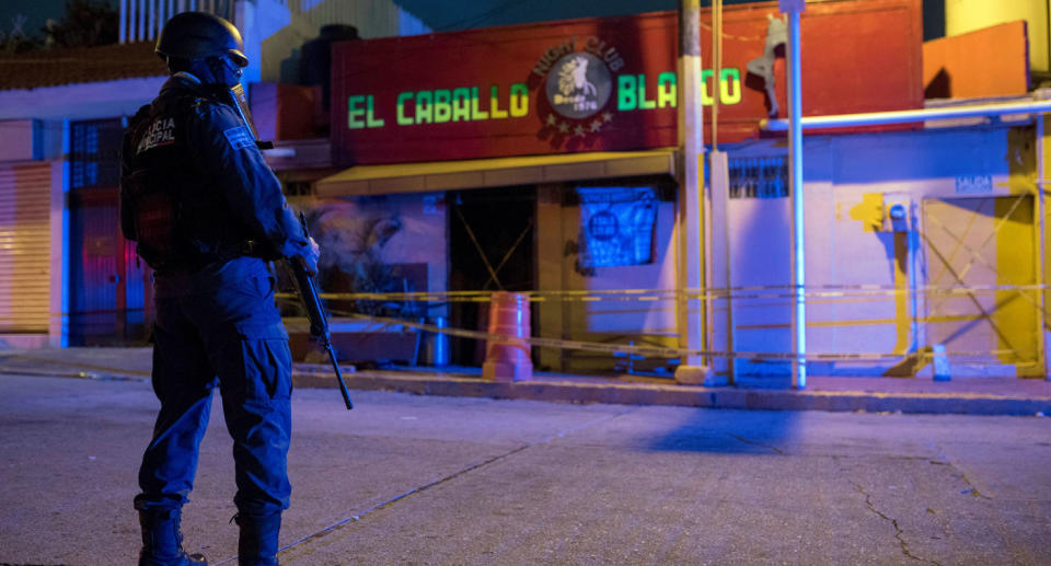 Armed officer outside El Caballo Blanco where a gang-lit fire killed 26 patrons.