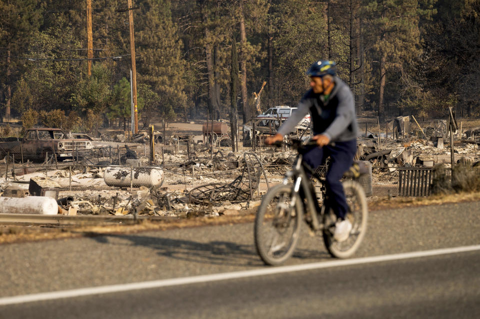 A bicyclist passes Wakefield Ave. homes destroyed by the Mill Fire on Saturday, Sept. 3, 2022, in Weed, Calif. (AP Photo/Noah Berger)