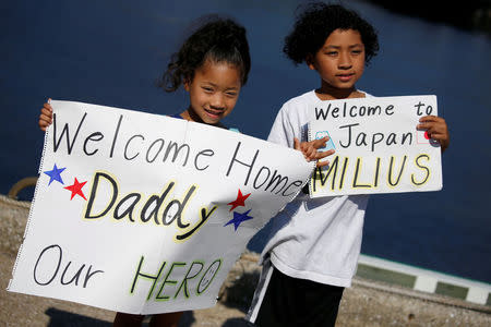 Family members of a crew hold signs, upon the arrival the U.S. guided-missile destroyer USS Milius (DDG69), that joins Forward Deployed Naval Forces at the U.S. naval base in Yokosuka, Japan May 22, 2018. REUTERS/Issei Kato