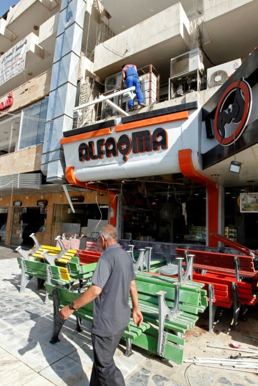 Iraqis check a popular ice cream shop in Baghdad's Karrada district on May 30, 2017 in the aftermath of a suicide bombing that killed at least 16 people