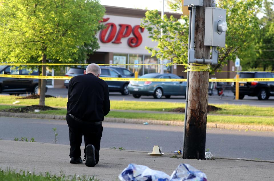 Fr. Rob Wozniak, pastor of St. Pius X Catholic Church in Getzville, N.Y., a suburb of Buffalo, kneels in prayer May 15, 2022 across the street from the Tops supermarket where a gunman killed ten people Saturday.