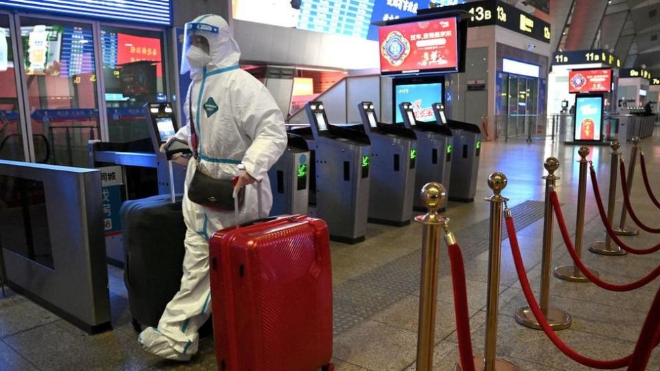 A passenger at the train station in Beijing wearing full-body protective equipment against Covid