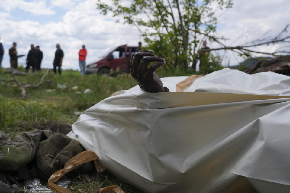 La mano marchita de un soldado ruso muerto se asoma de una bolsa para cadáveres durante la exhumación de soldados rusos fallecidos en sus antiguas posiciones, el miércoles 18 de mayo de 2022, cerca del pueblo de Malaya Rohan, en las afueras de Járkiv. (AP Foto/Andrii Marienko)